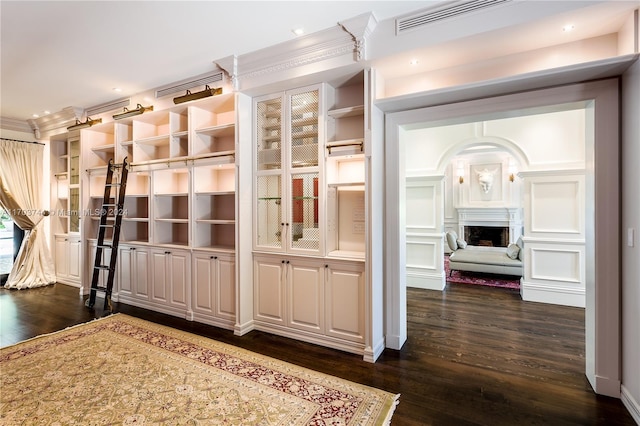 interior space with dark hardwood / wood-style floors, built in features, and ornamental molding