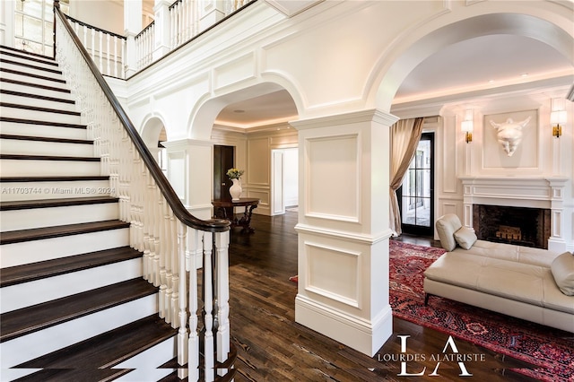 staircase featuring hardwood / wood-style flooring, decorative columns, and ornamental molding