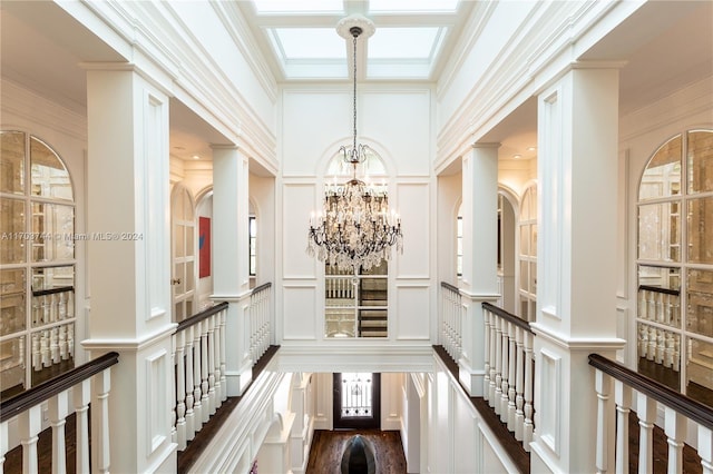 corridor with a chandelier, a towering ceiling, dark wood-type flooring, and ornamental molding