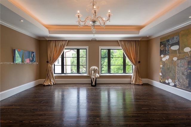 empty room with a tray ceiling, a chandelier, and dark hardwood / wood-style floors