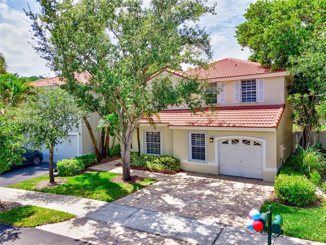 mediterranean / spanish-style home with a tiled roof, decorative driveway, and stucco siding