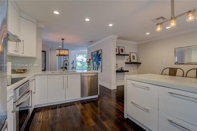 kitchen featuring visible vents, ornamental molding, a peninsula, stainless steel appliances, and a sink