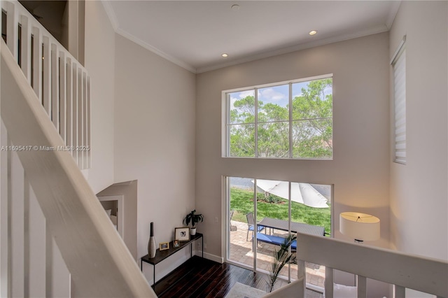 interior space featuring recessed lighting, a high ceiling, ornamental molding, wood finished floors, and baseboards