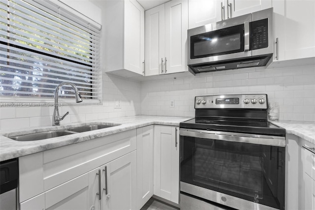 kitchen featuring light stone countertops, white cabinetry, sink, and appliances with stainless steel finishes