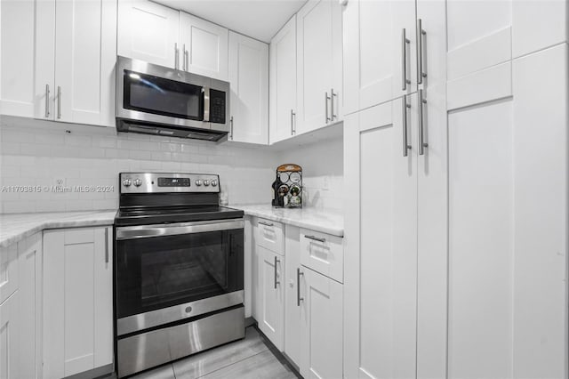 kitchen featuring light stone countertops, stainless steel appliances, and white cabinetry