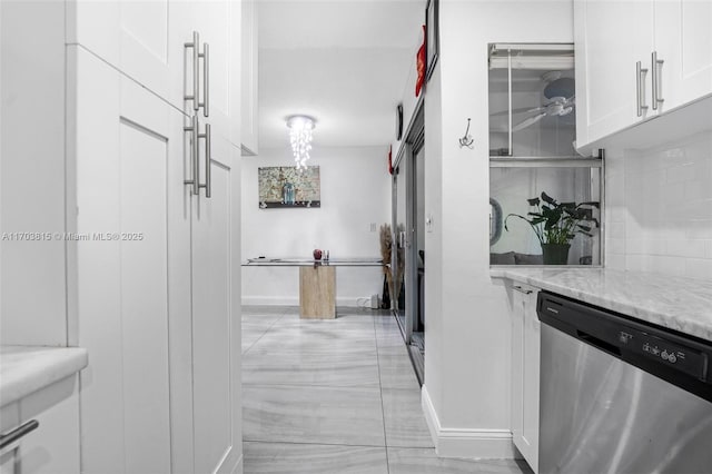 kitchen featuring tasteful backsplash, baseboards, white cabinets, dishwasher, and light stone counters