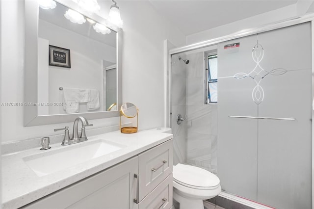 bathroom featuring a shower with door, vanity, and toilet