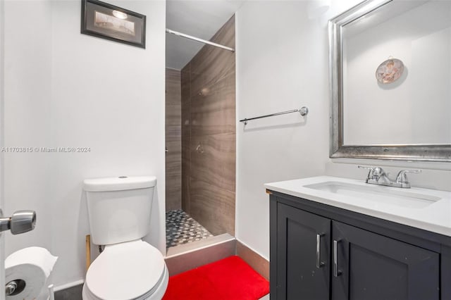 bathroom featuring a tile shower, vanity, and toilet