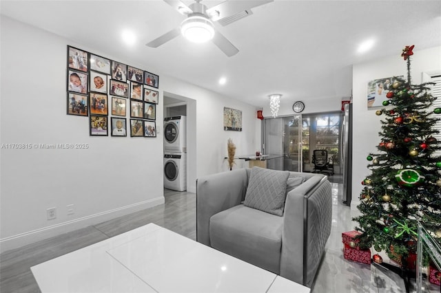 living area with stacked washer / dryer, visible vents, ceiling fan, and baseboards