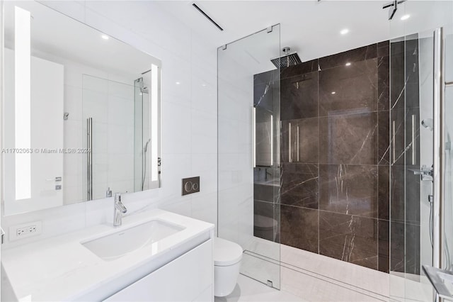 bathroom featuring vanity, toilet, tile walls, and a tile shower