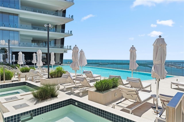 view of swimming pool with a water view and a hot tub