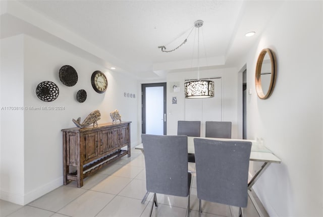 dining room featuring light tile patterned flooring and a tray ceiling