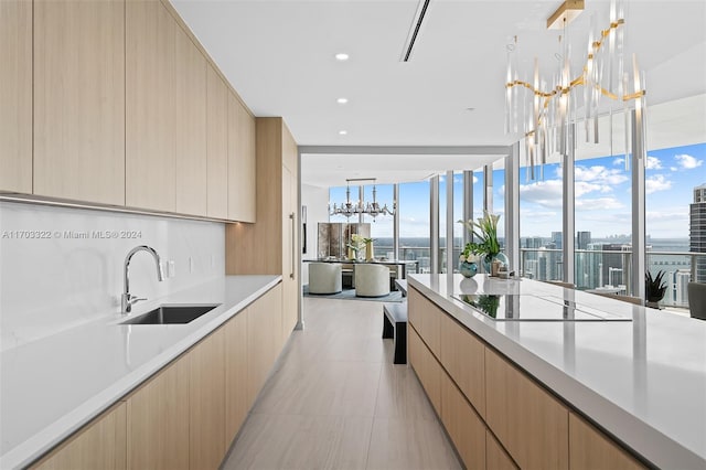 kitchen with light brown cabinetry, sink, floor to ceiling windows, black electric cooktop, and a chandelier