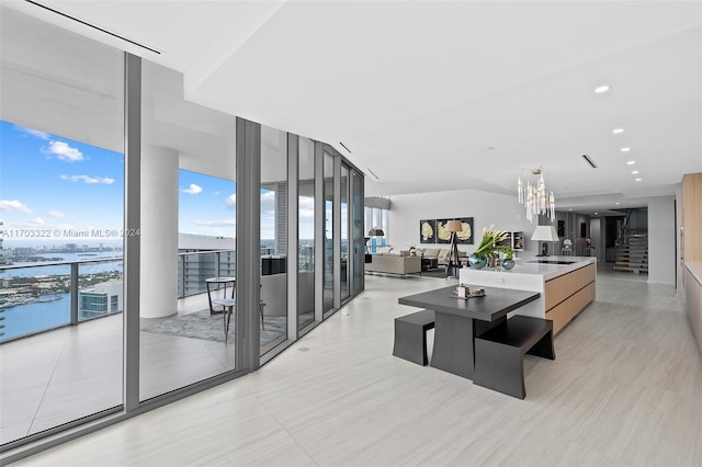 living room with a wall of windows, a water view, and a chandelier