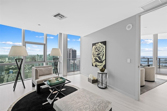 sitting room with a water view, light hardwood / wood-style flooring, and floor to ceiling windows