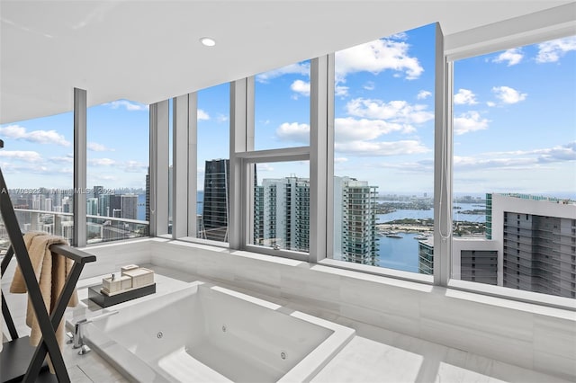 bathroom with a tub, a healthy amount of sunlight, a water view, and floor to ceiling windows