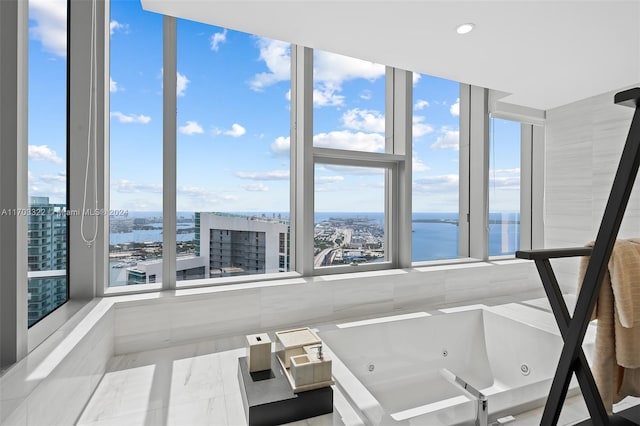 bathroom featuring a wall of windows, a water view, and a bath