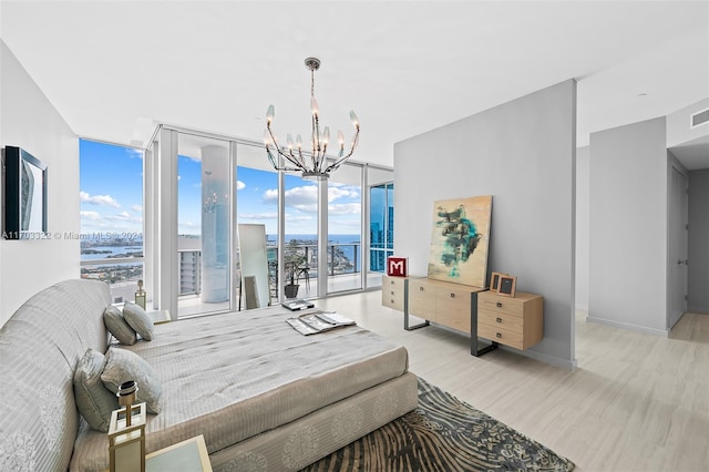 bedroom featuring light wood-type flooring, a water view, floor to ceiling windows, access to exterior, and a notable chandelier