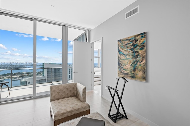 sitting room featuring a water view and floor to ceiling windows