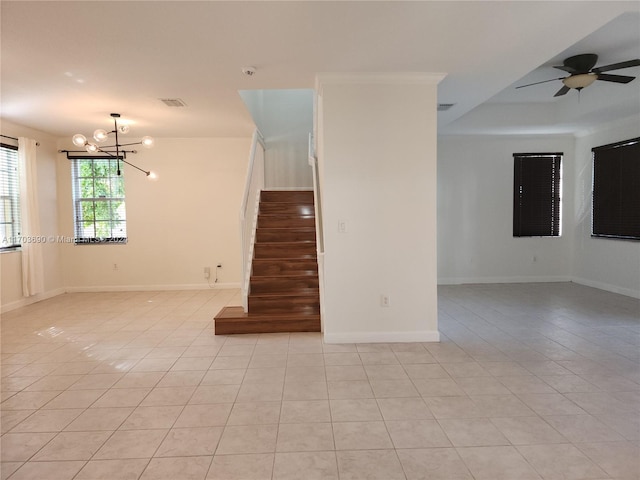 tiled empty room featuring ceiling fan with notable chandelier