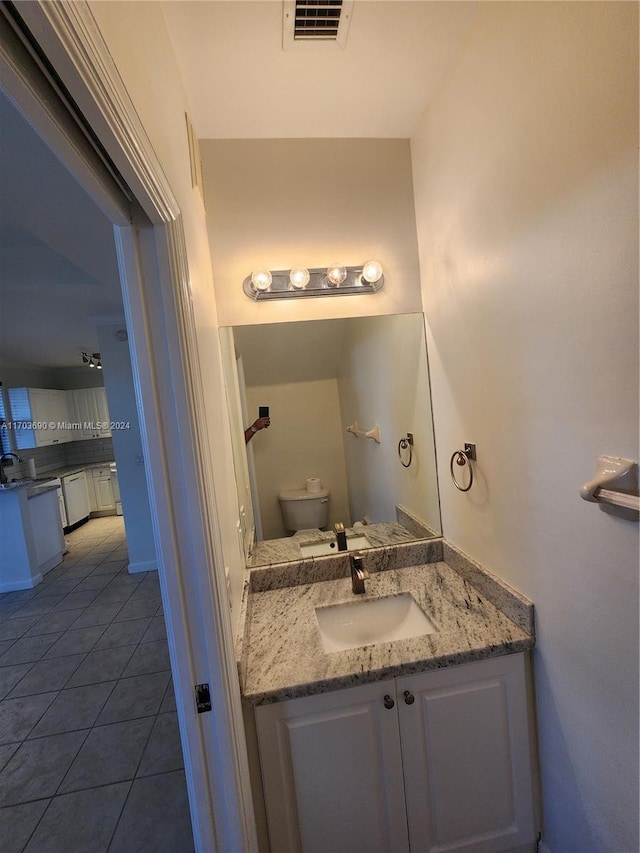 bathroom with toilet, vanity, and tile patterned floors