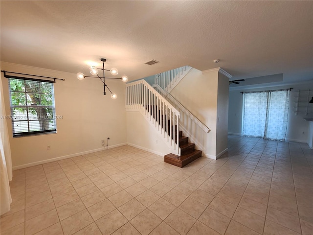 interior space with light tile patterned floors, a textured ceiling, crown molding, and a notable chandelier