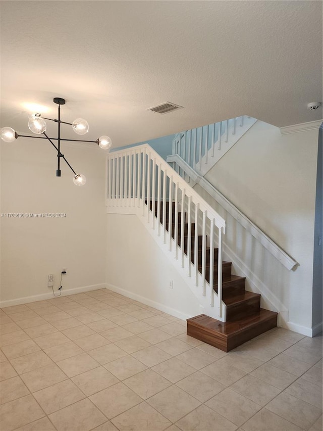 stairs featuring tile patterned floors, a textured ceiling, and an inviting chandelier