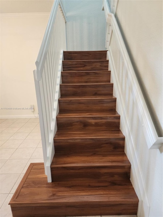 staircase featuring tile patterned floors and crown molding