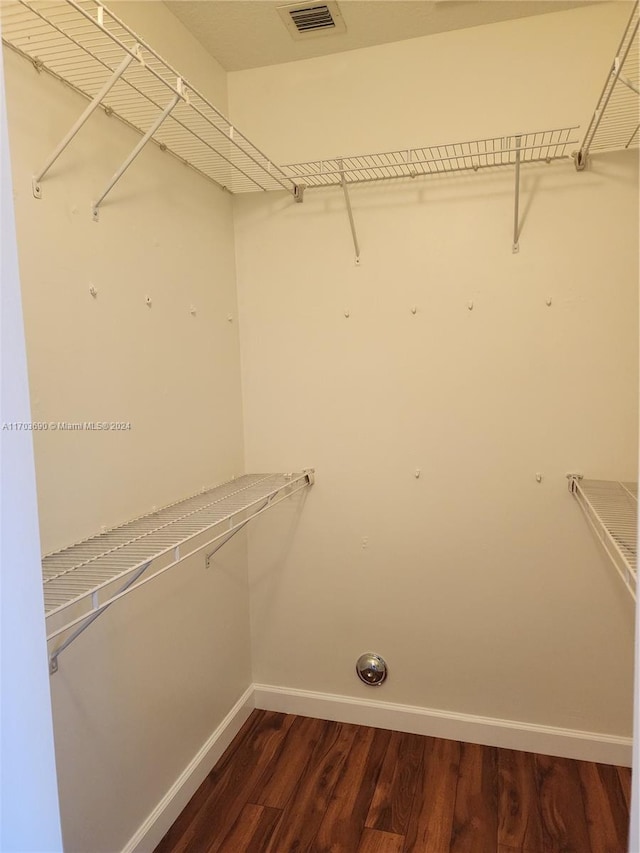 walk in closet with dark wood-type flooring