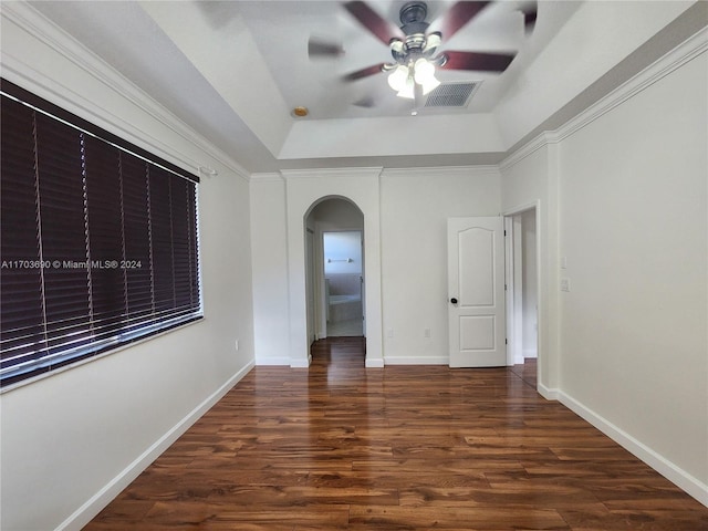 unfurnished room with ceiling fan, dark hardwood / wood-style flooring, ornamental molding, and a tray ceiling