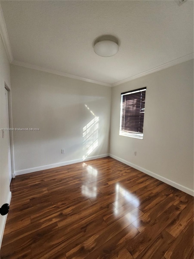 empty room with dark hardwood / wood-style flooring and crown molding