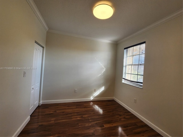 unfurnished room featuring dark wood-type flooring, a textured ceiling, and ornamental molding