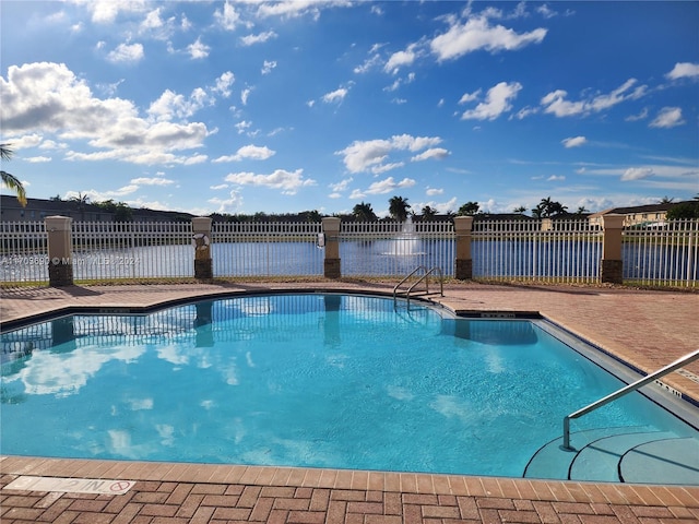 view of swimming pool with a patio area and a water view