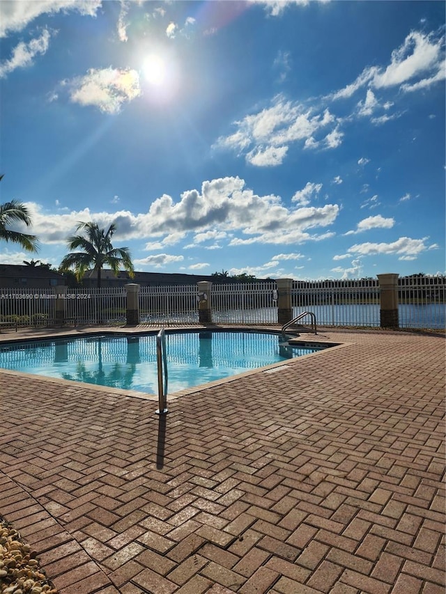 view of swimming pool featuring a water view and a patio