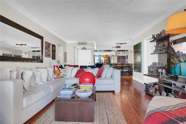 living room with a textured ceiling, crown molding, and dark wood-type flooring