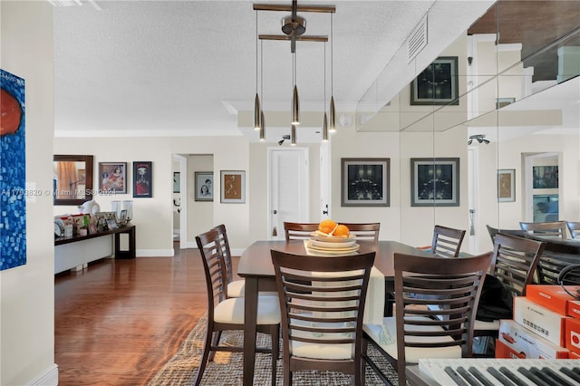 dining area featuring dark hardwood / wood-style flooring, ornamental molding, and a textured ceiling