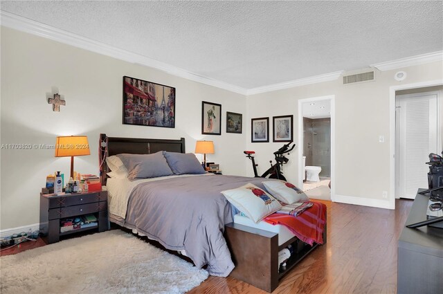 bedroom featuring hardwood / wood-style floors, ensuite bathroom, crown molding, and a textured ceiling