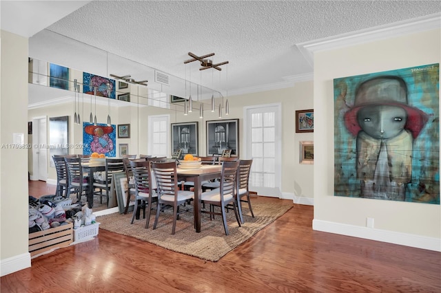 dining area with crown molding, a textured ceiling, and hardwood / wood-style flooring