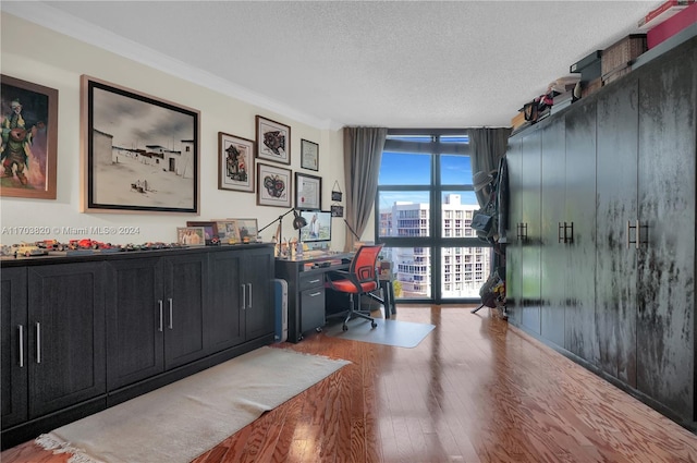 office featuring hardwood / wood-style floors, floor to ceiling windows, ornamental molding, and a textured ceiling