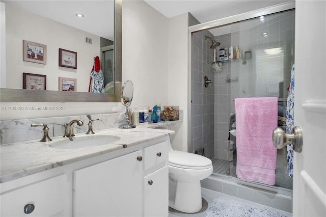 bathroom with vanity, toilet, and a shower with shower door