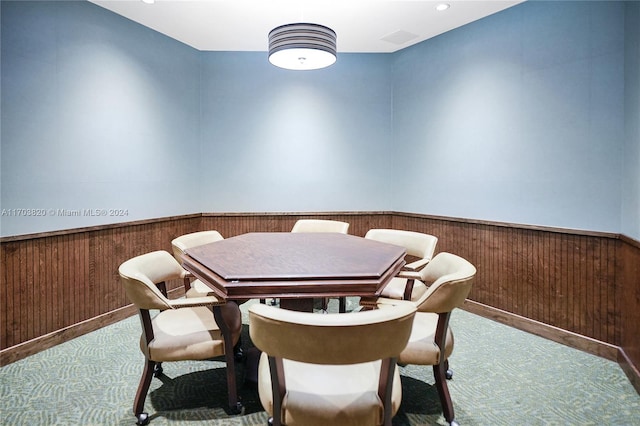 dining room with light colored carpet and wooden walls