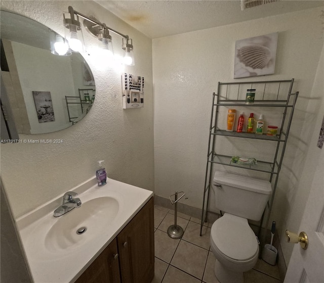 bathroom with toilet, a textured ceiling, vanity, and tile patterned floors