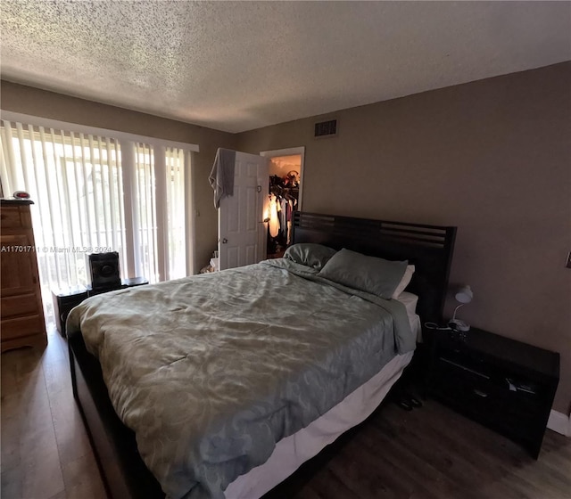 bedroom featuring a textured ceiling, a spacious closet, dark wood-type flooring, and a closet