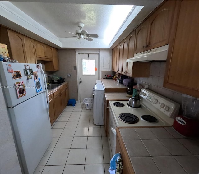 kitchen featuring white appliances, a textured ceiling, ceiling fan, light tile patterned floors, and tile counters