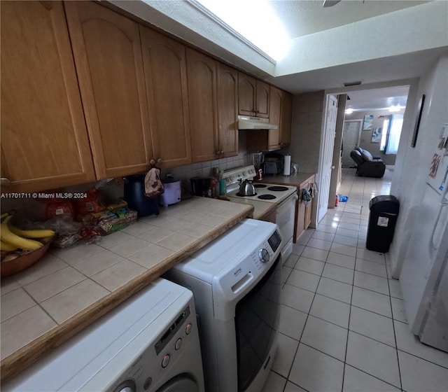 clothes washing area with light tile patterned floors and washer and clothes dryer