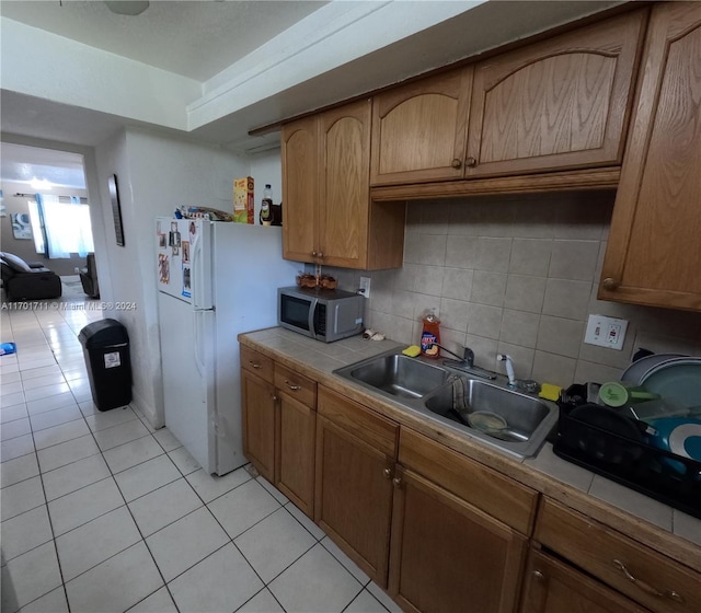 kitchen featuring decorative backsplash, light tile patterned floors, tile counters, and sink