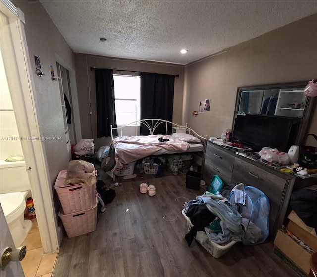 bedroom featuring hardwood / wood-style flooring, a textured ceiling, and connected bathroom