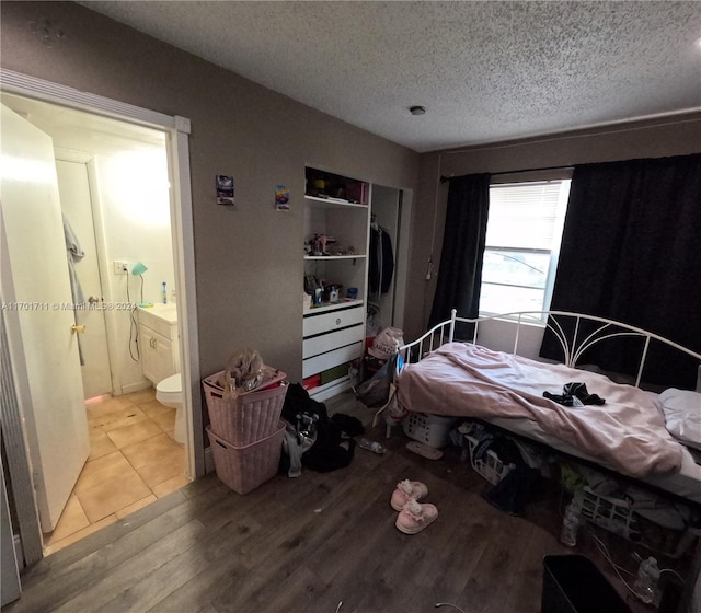 bedroom featuring a textured ceiling, hardwood / wood-style flooring, and connected bathroom