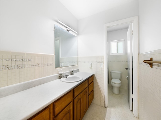 bathroom featuring vanity, toilet, and tile walls