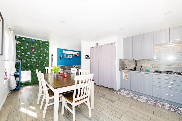 kitchen with light wood-type flooring, stainless steel gas stovetop, and gray cabinetry